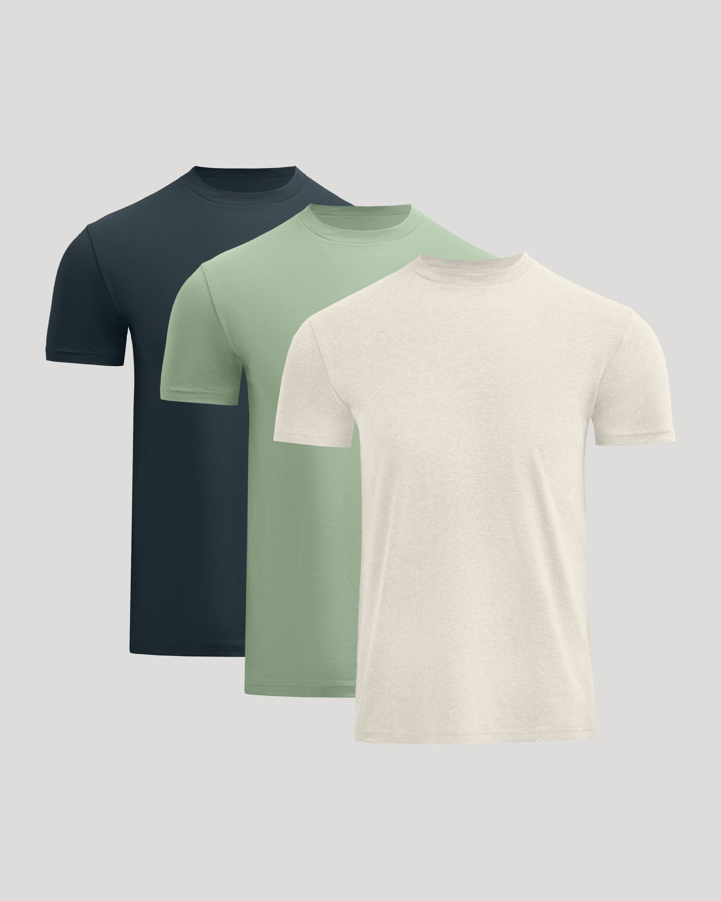 Three short-sleeve shirts in black, green, and beige on a light gray background
