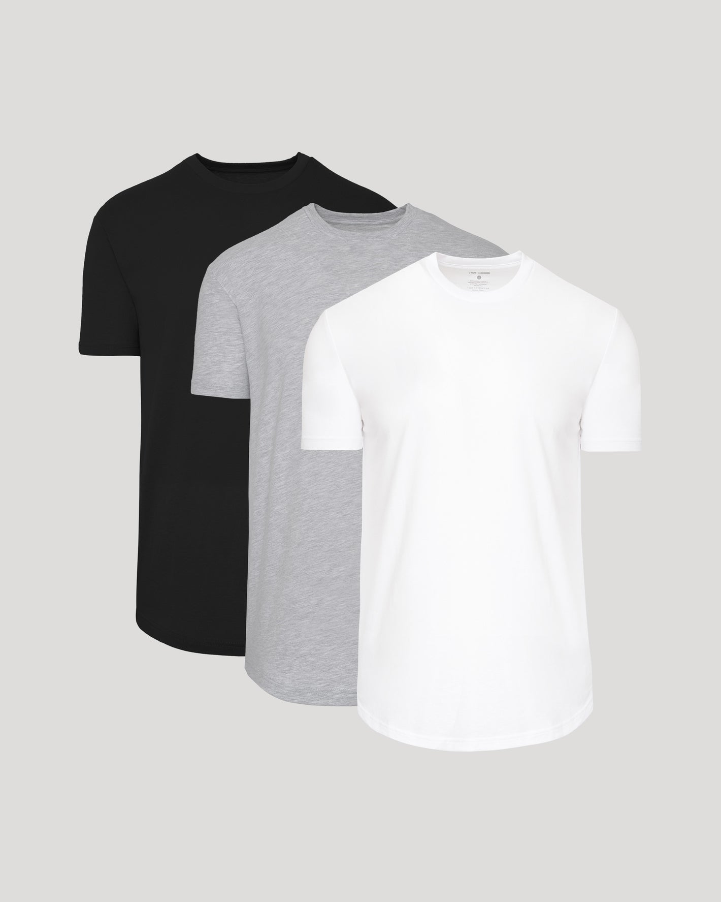 Three plain t-shirts in black, gray, and white on a light gray background