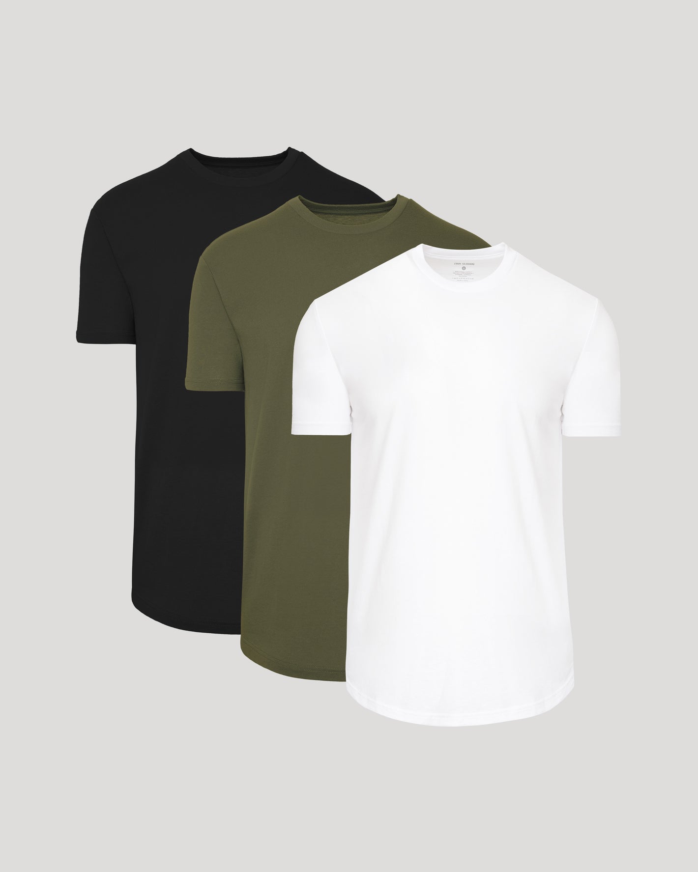 Three plain t-shirts in black, green, and white on a light gray background