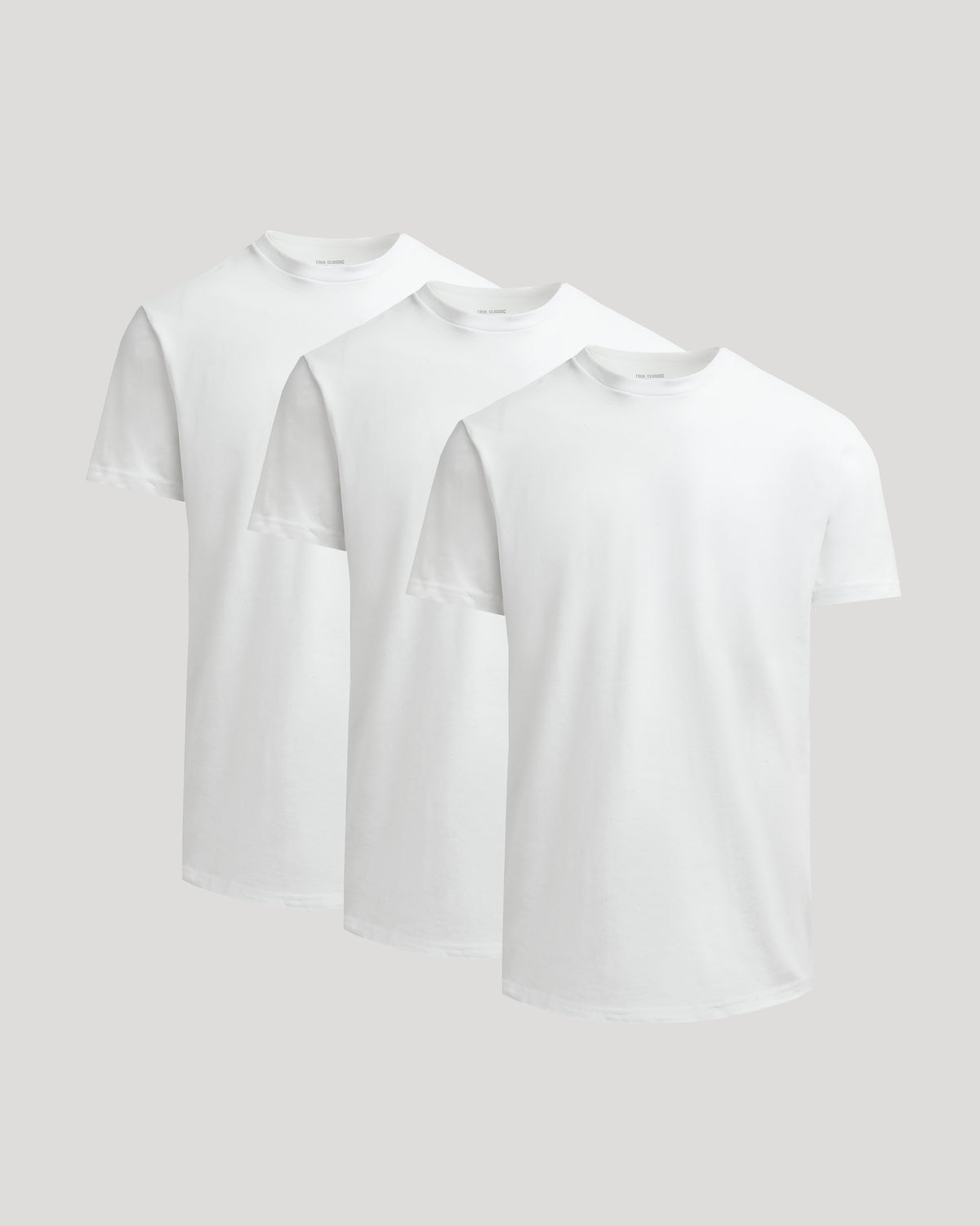 Three white True Classic Men's Heavyweight Curved Hem Crew – Premium Heavyweight Cotton Blend, Modern Athletic Fit, Structured Everyday T-Shirts displayed against a light background.