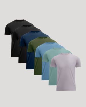 Six short-sleeve crew-neck t-shirts in different colors, arranged in a diagonal stack from back to front on a light gray background. The colors include black, charcoal, navy, olive green, sky blue, mint green, and light lavender.