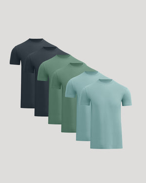 Five short-sleeve crew-neck t-shirts in a staggered overlapping arrangement, shown in dark navy, charcoal, sage green, mint green, and light aqua on a solid light gray background.