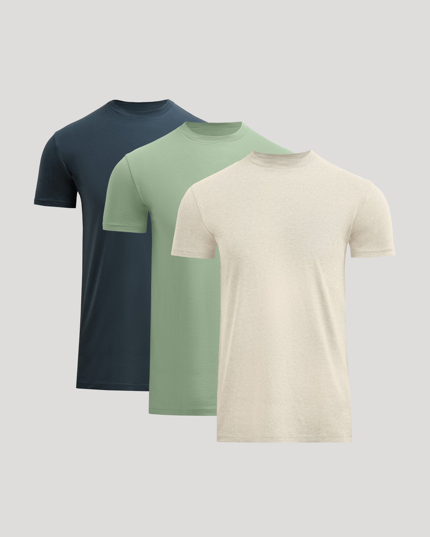 Three plain t-shirts in navy, green, and beige on a light gray background