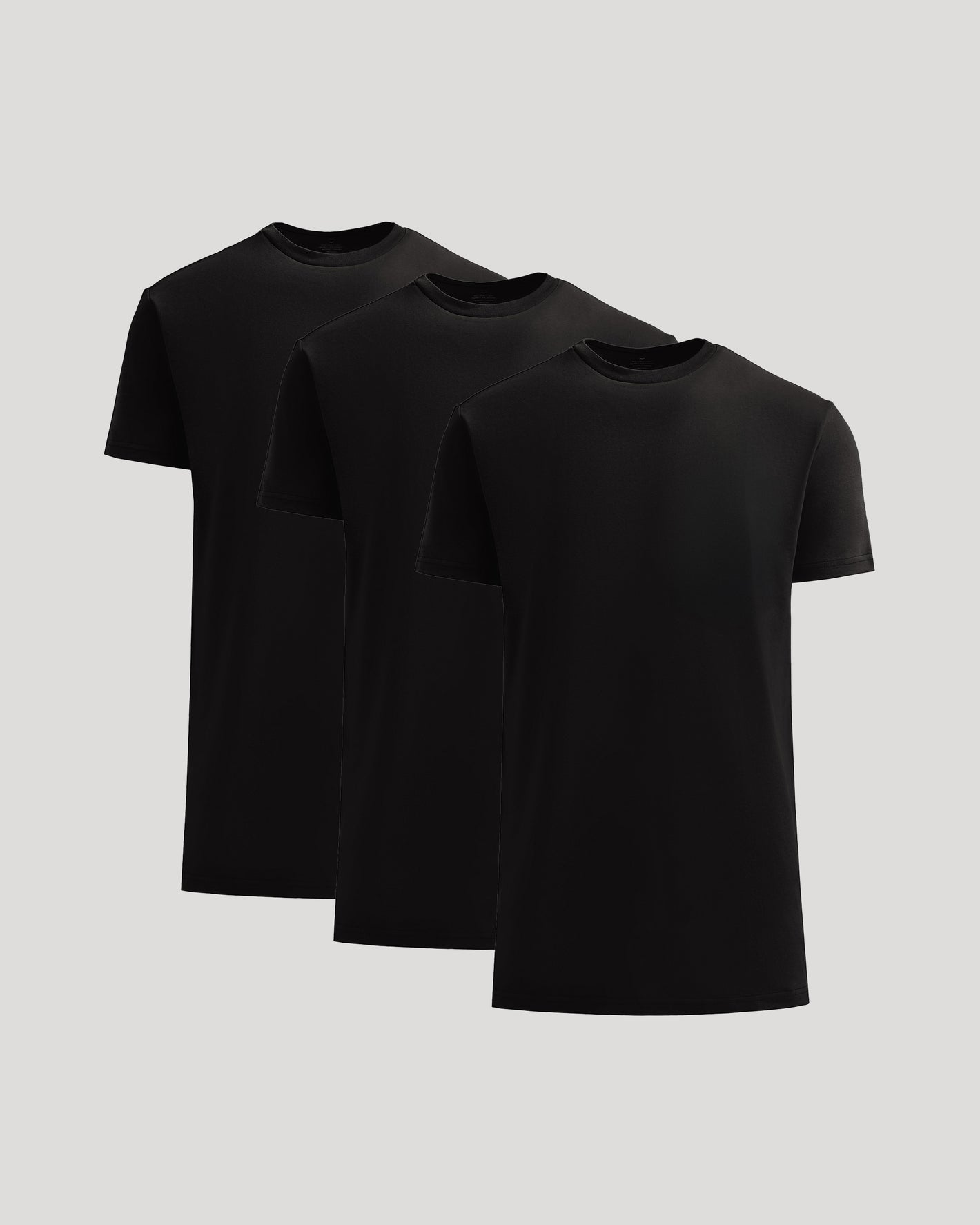 Three black t-shirts stacked on a light gray background