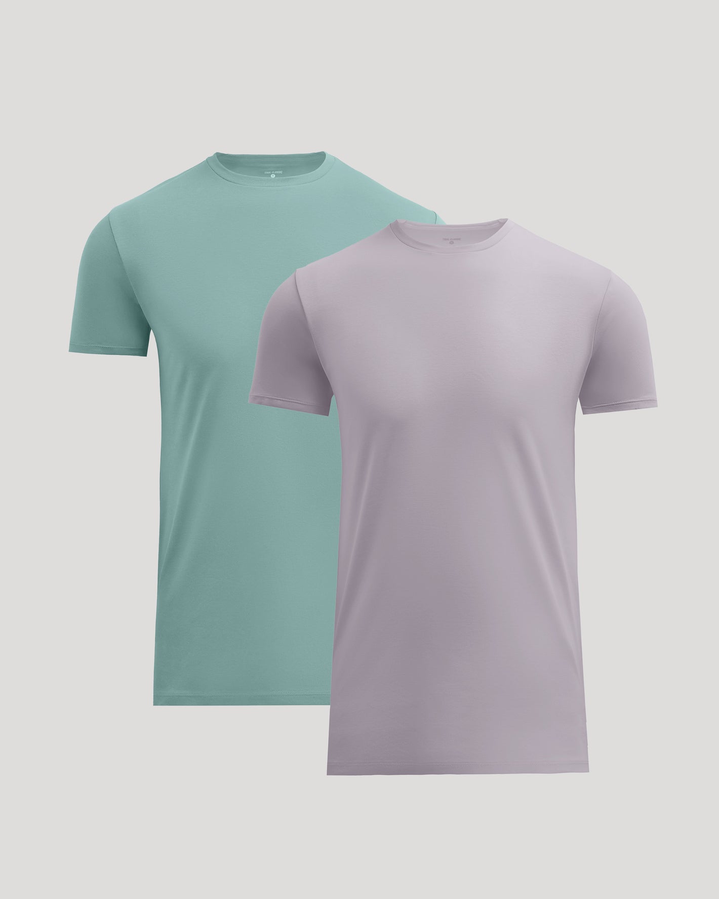 Two short-sleeve crew-neck t-shirts shown on a light gray background, with one in mint green and one in light lavender. The lavender shirt is positioned in front and slightly overlaps the mint green shirt.