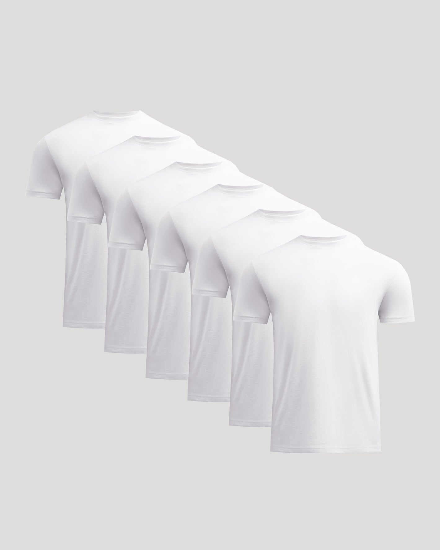 Multiple white t-shirts stacked on a light gray background
