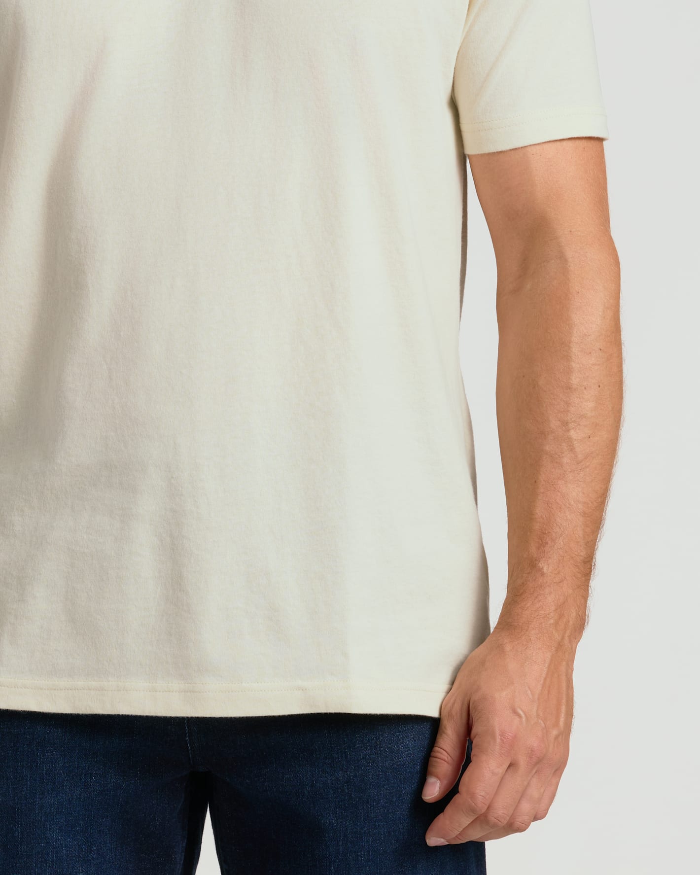 Person wearing a plain white t-shirt and dark pants on a light background