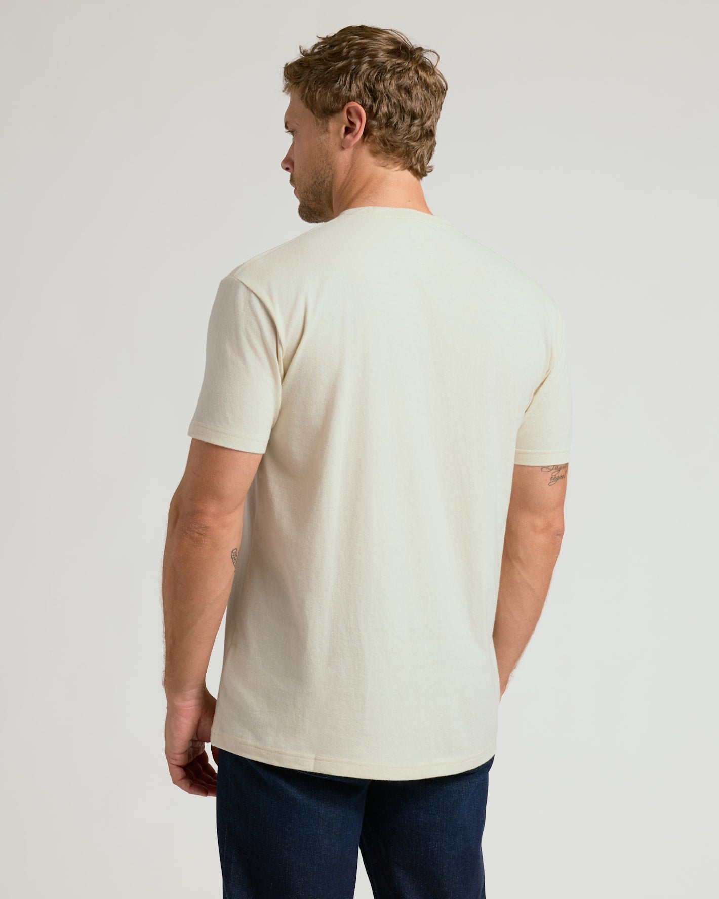 Man wearing a plain white t-shirt on a light gray background