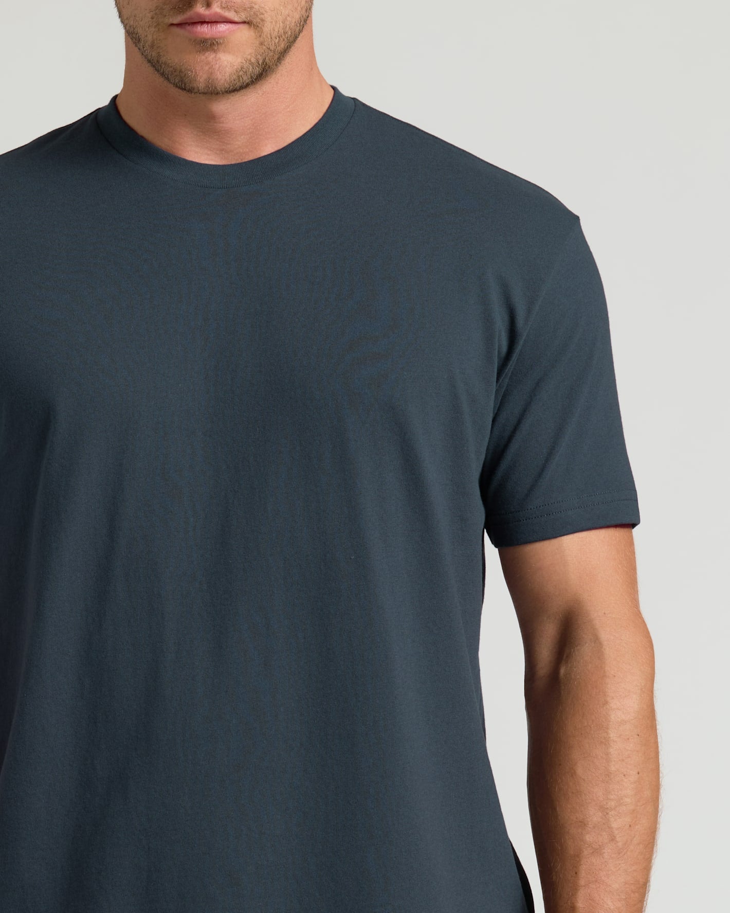 Man wearing a plain dark gray t-shirt against a light gray background