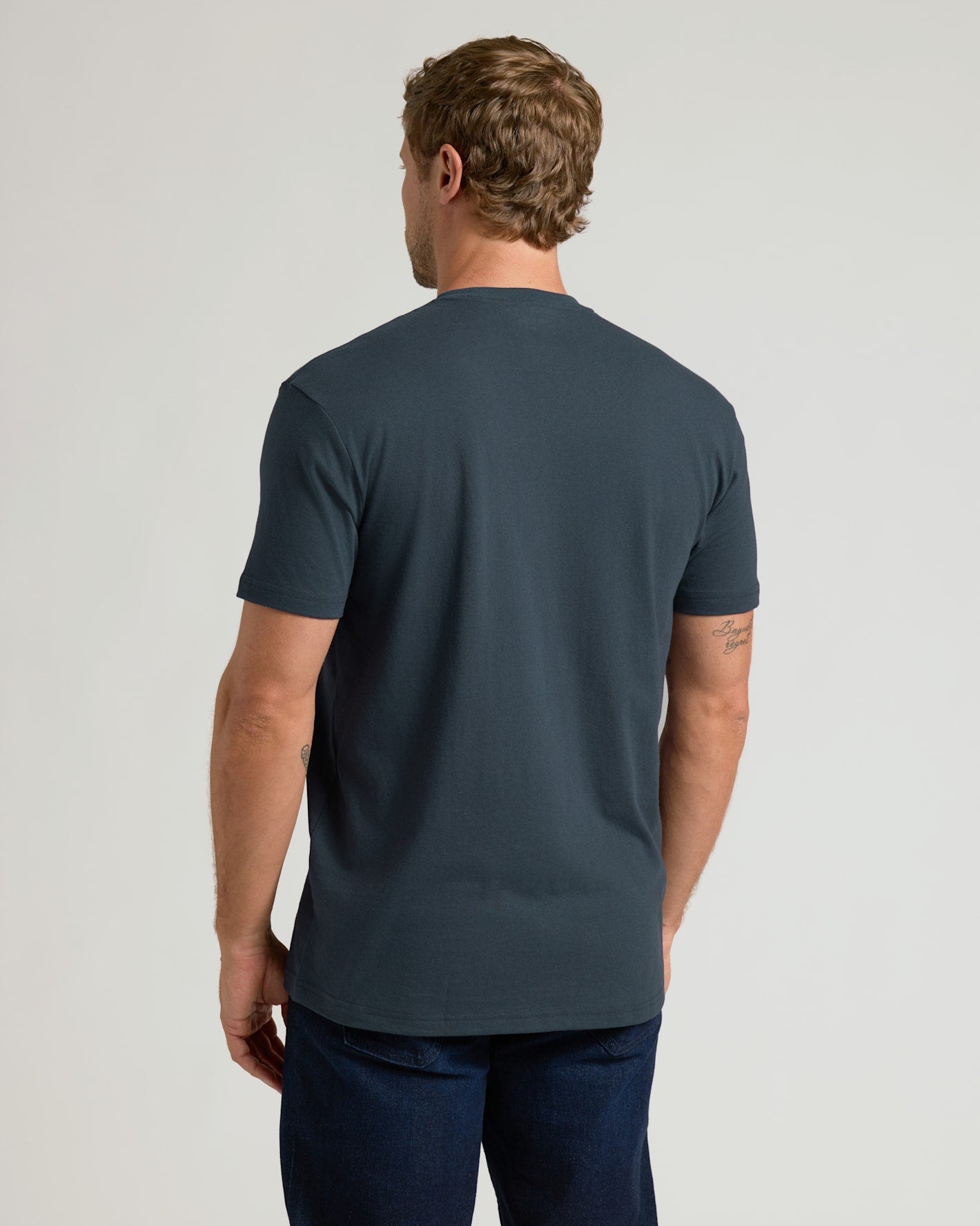 Man wearing a dark blue t-shirt on a light gray background
