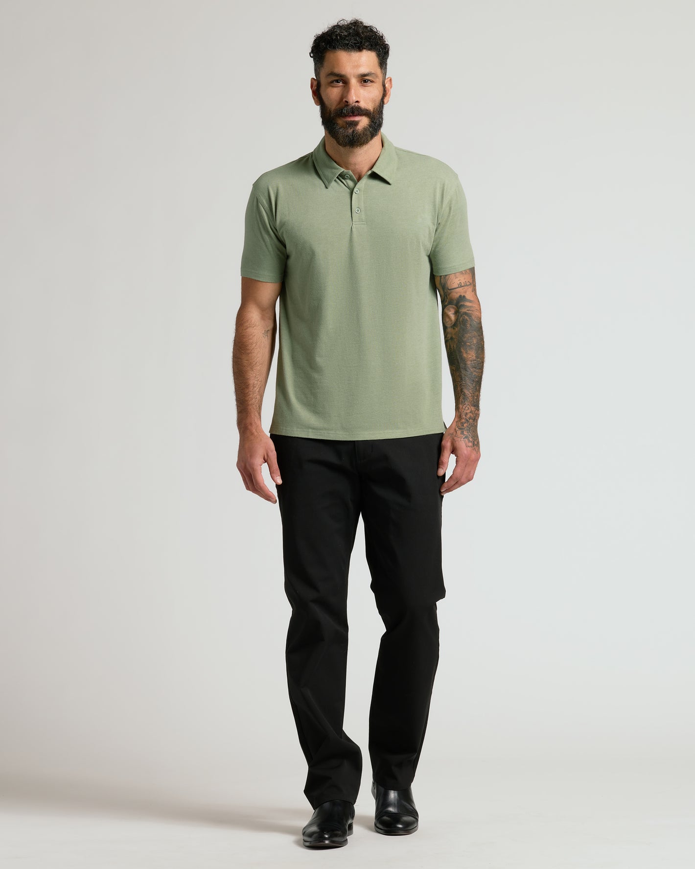 Man wearing Dark Heather Bay Green Classic Polo with black trousers.