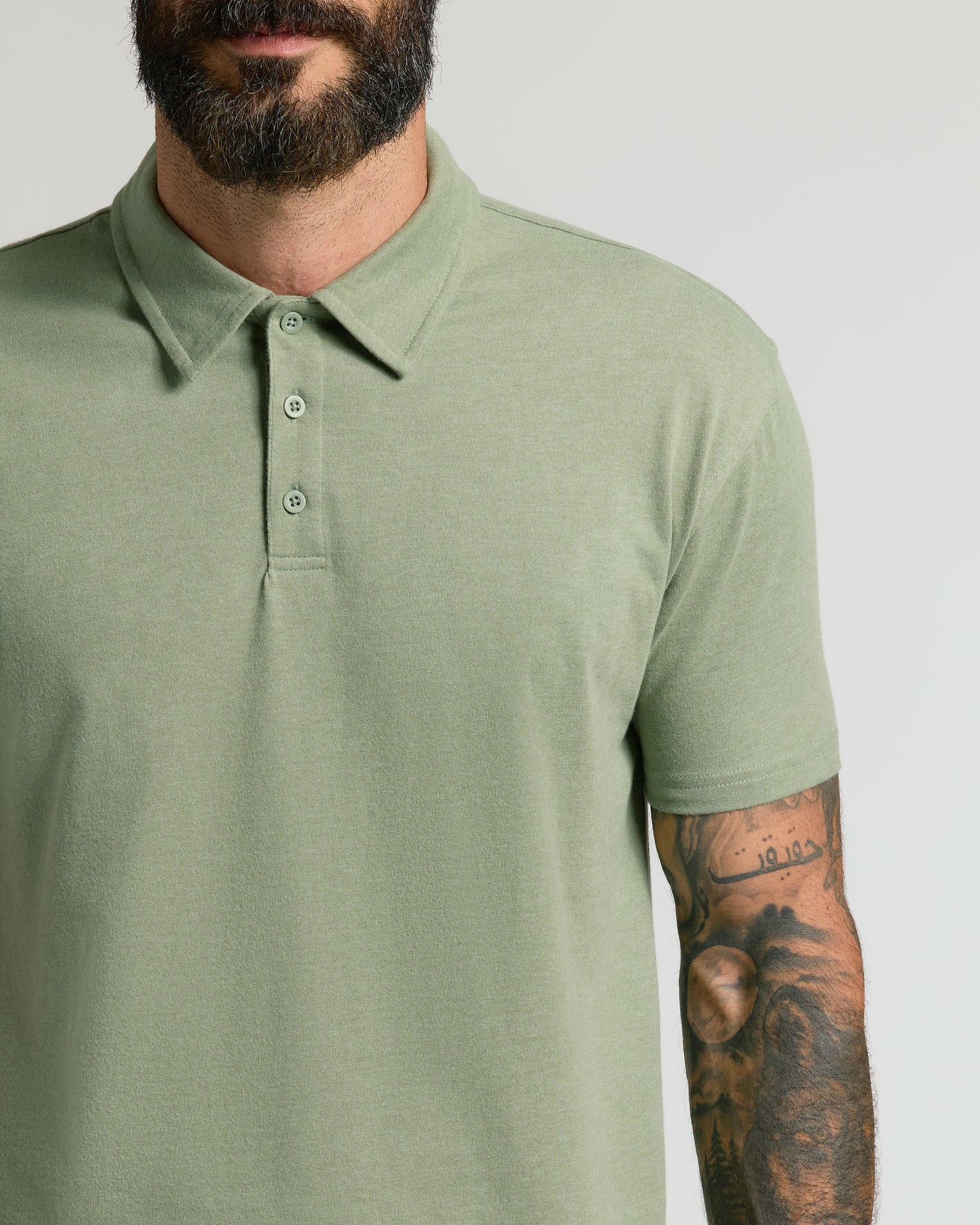 Man wearing Dark Heather Bay Green Classic Polo with tattooed arm.