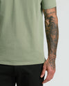 Person wearing Dark Heather Bay Green Classic Polo, showcasing tattooed arm.