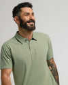Man in Dark Heather Bay Green Classic Polo, smiling with tattoo visible.