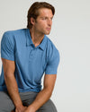 Young man wearing Dark Heather Blue Lake Classic Polo, seated thoughtfully.