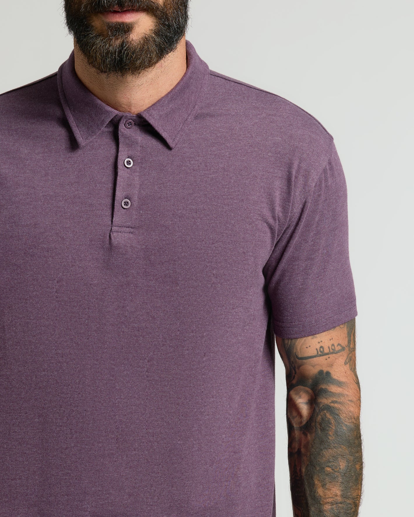 Man in Dark Heather Plum Classic Polo with tattooed arm.