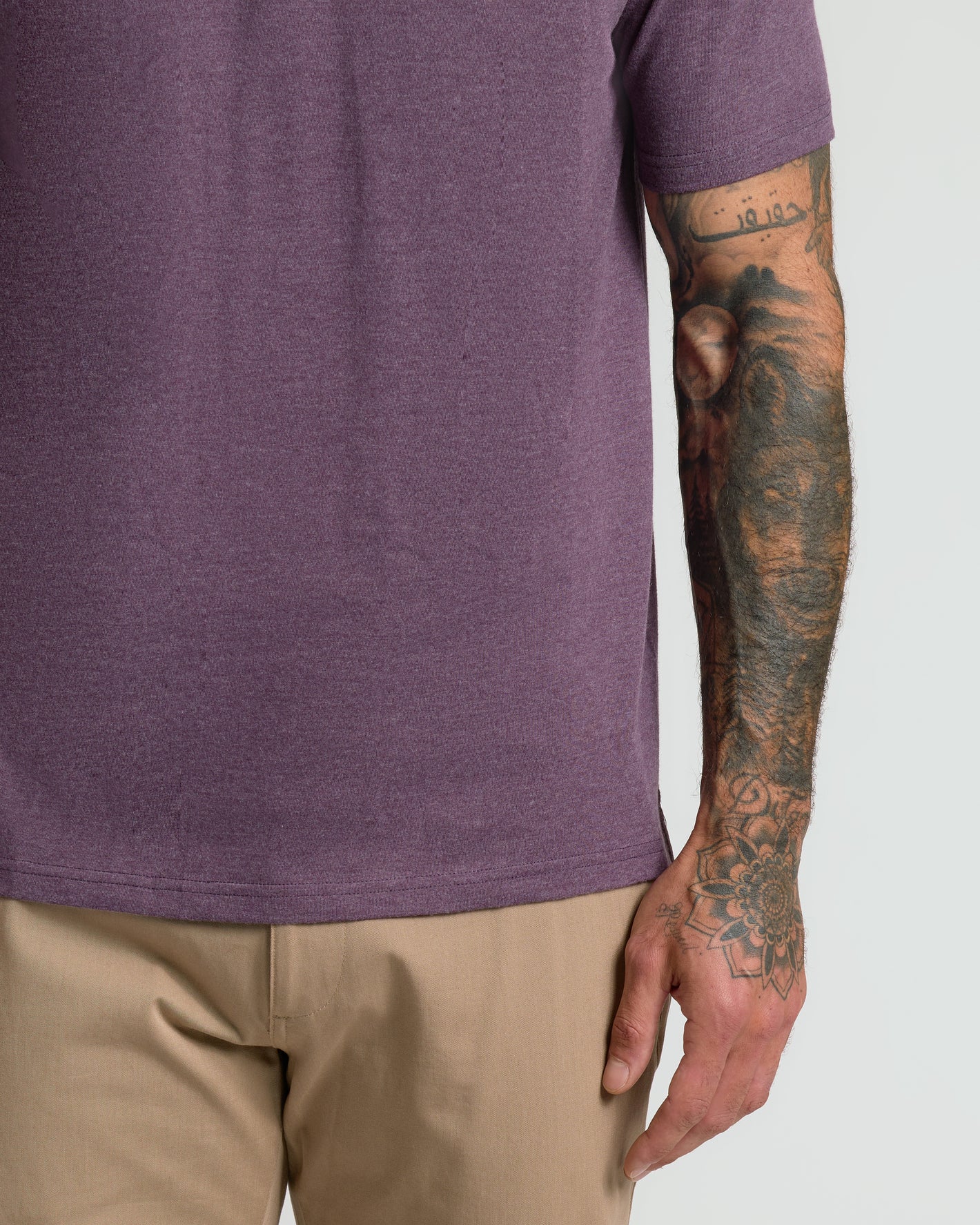 Dark Heather Plum Classic Polo with tattoos visible on forearm and hand.