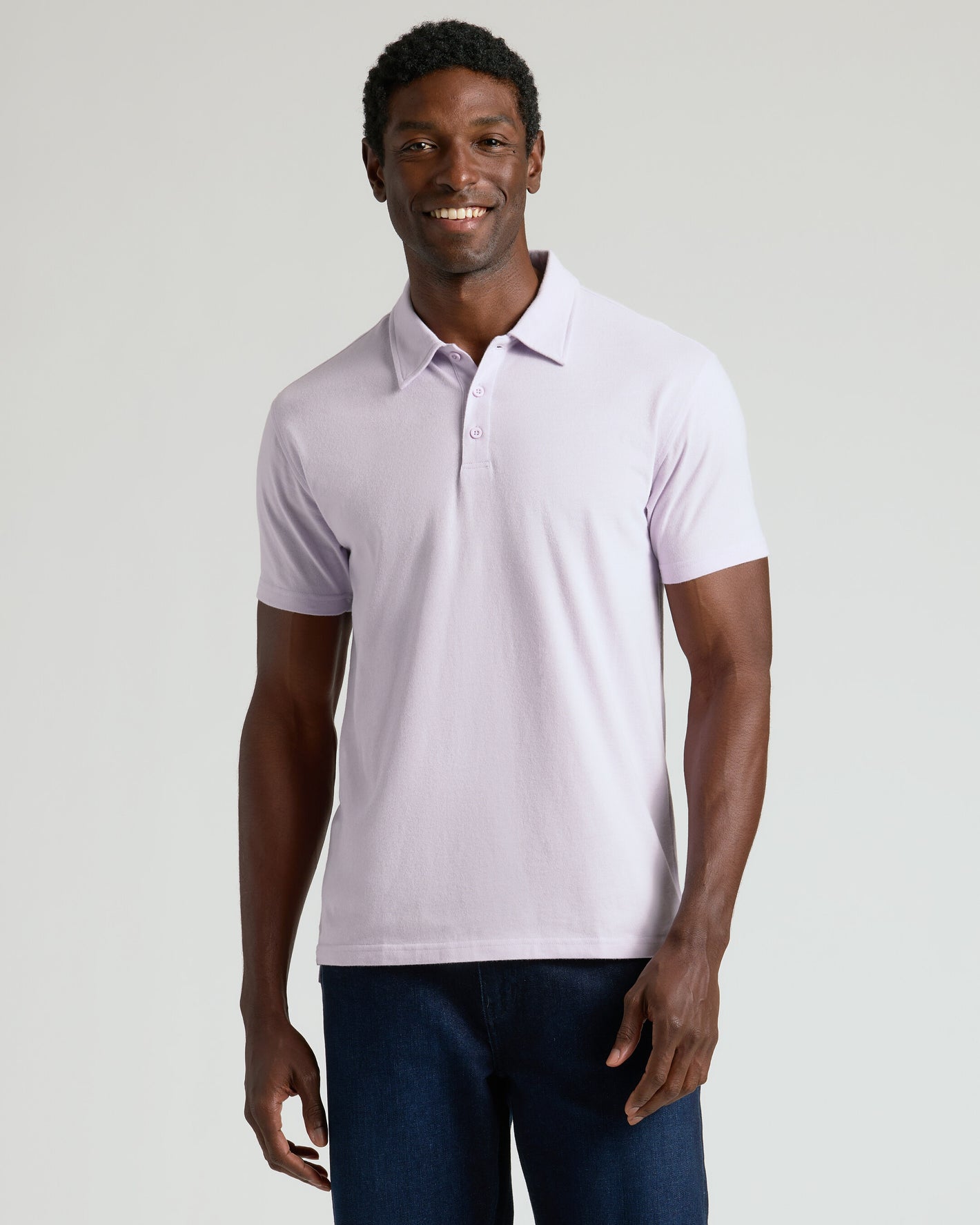 Man in Heather Orchid Classic Polo and dark jeans smiling.