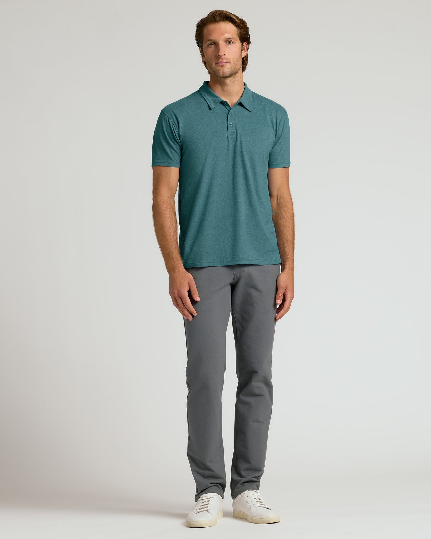 Man wearing Heather Seafarer Classic Polo with grey pants and white sneakers.