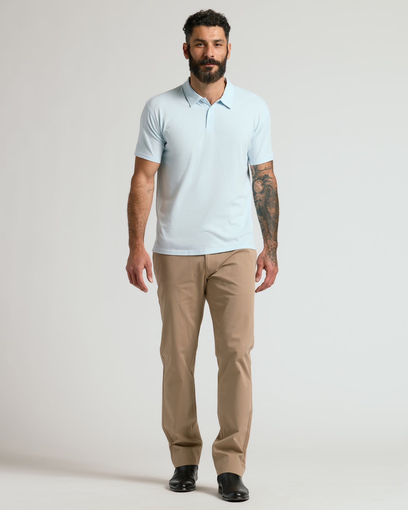 Man wearing Icicle Classic Polo with tattoos and khaki trousers.