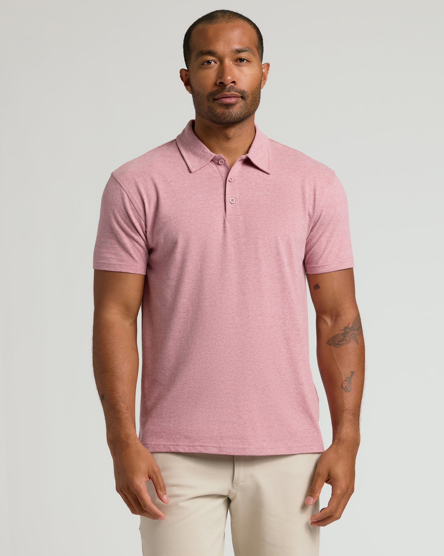 Man in Seasonal Classic Polo, heathered rose-pink, with tattoos, smart-casual look.