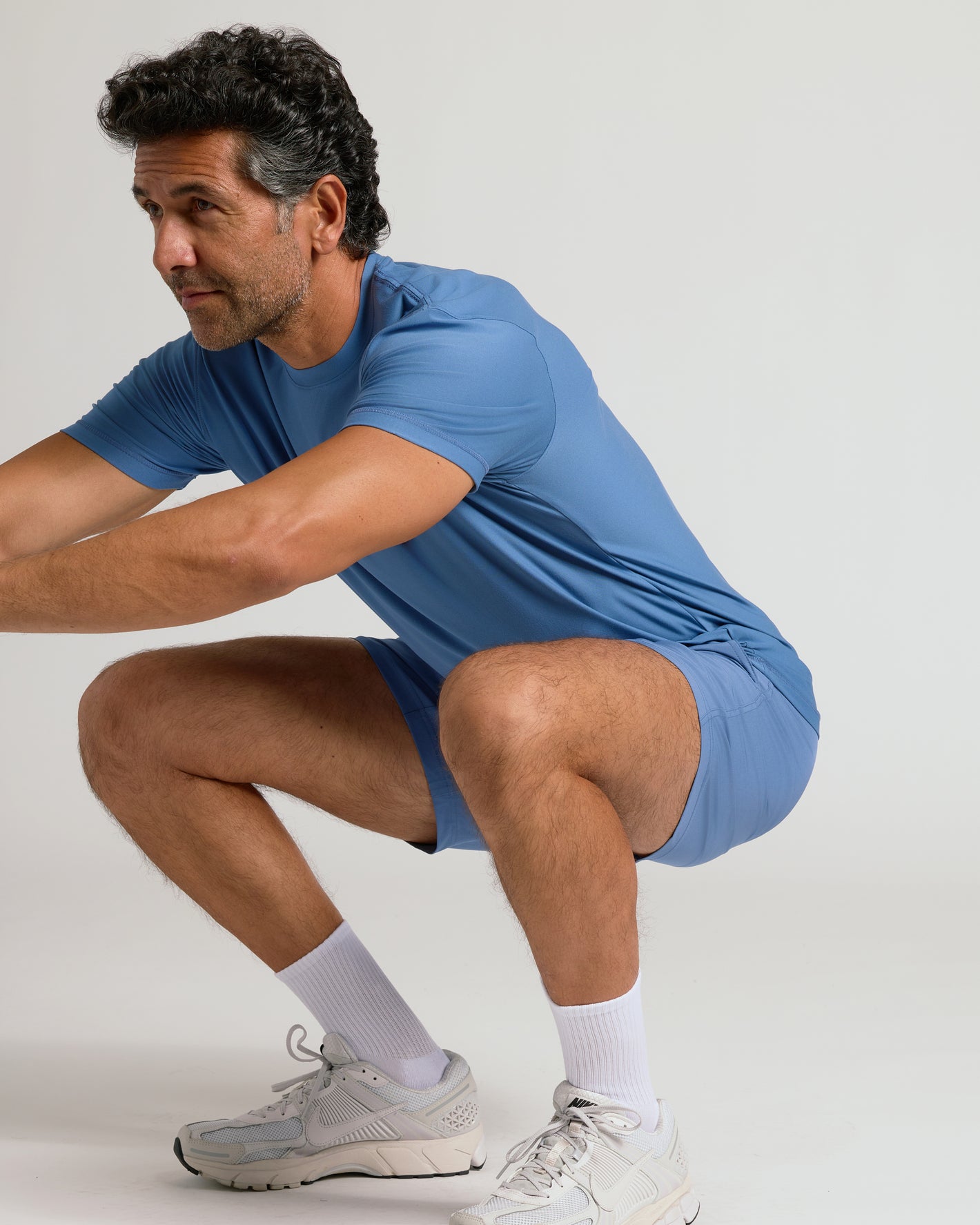 Man squatting in Azul Active Crew Neck Tee and matching shorts.