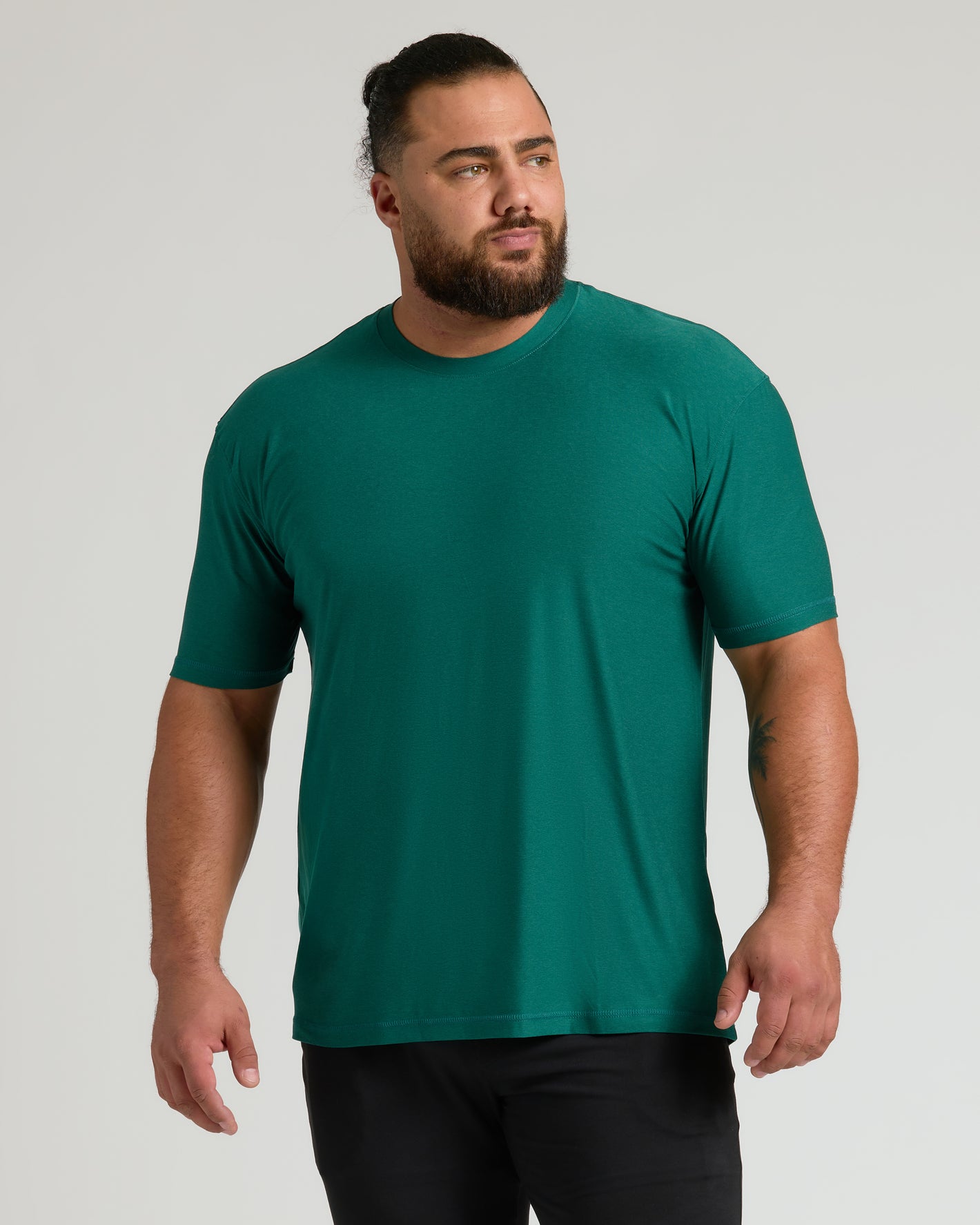 Man wearing Limited Spring Active Crew t-shirt, deep green, and black pants.