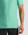 Person wearing a light green t-shirt and black pants on a white background