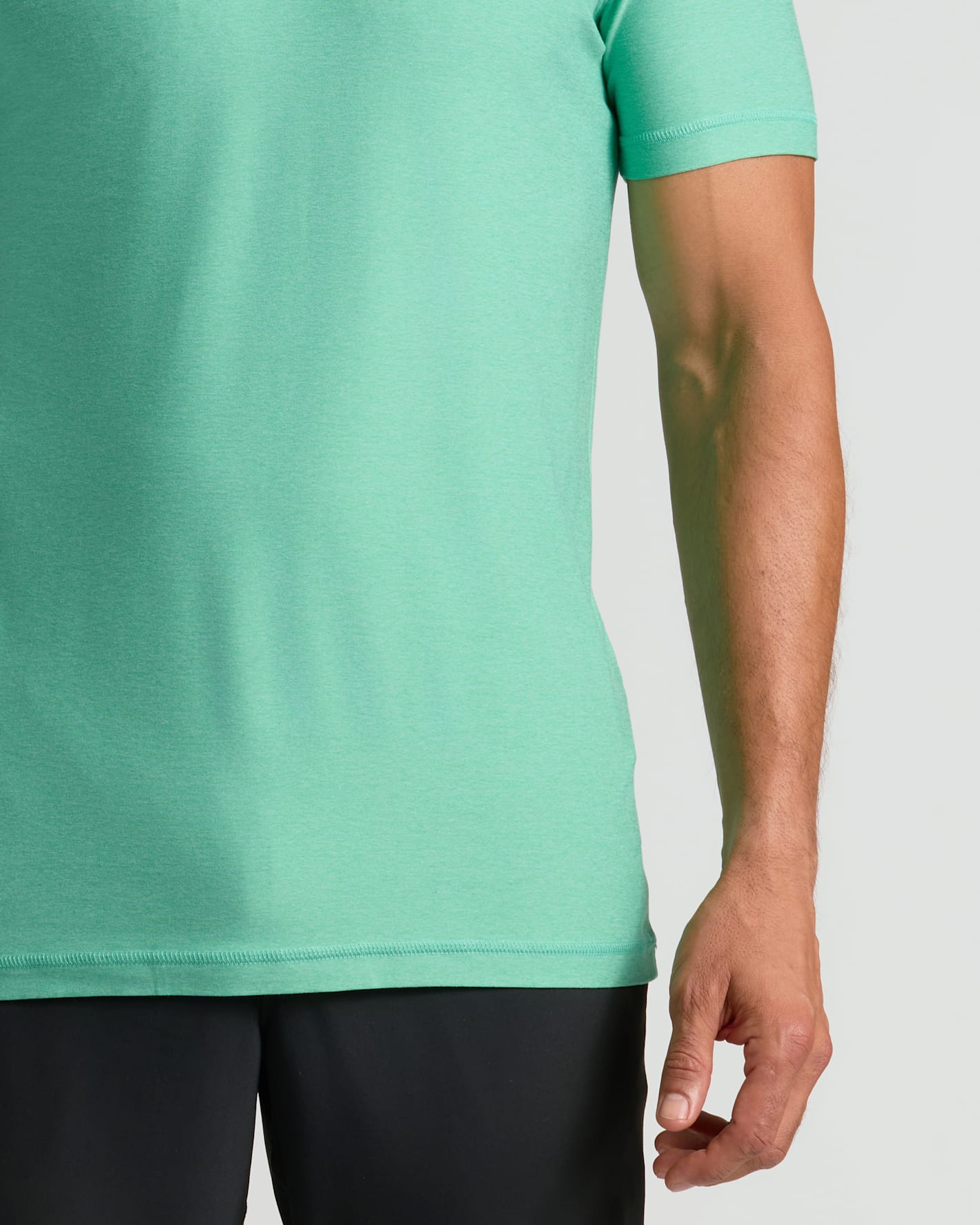 Person wearing a light green t-shirt and black pants on a white background