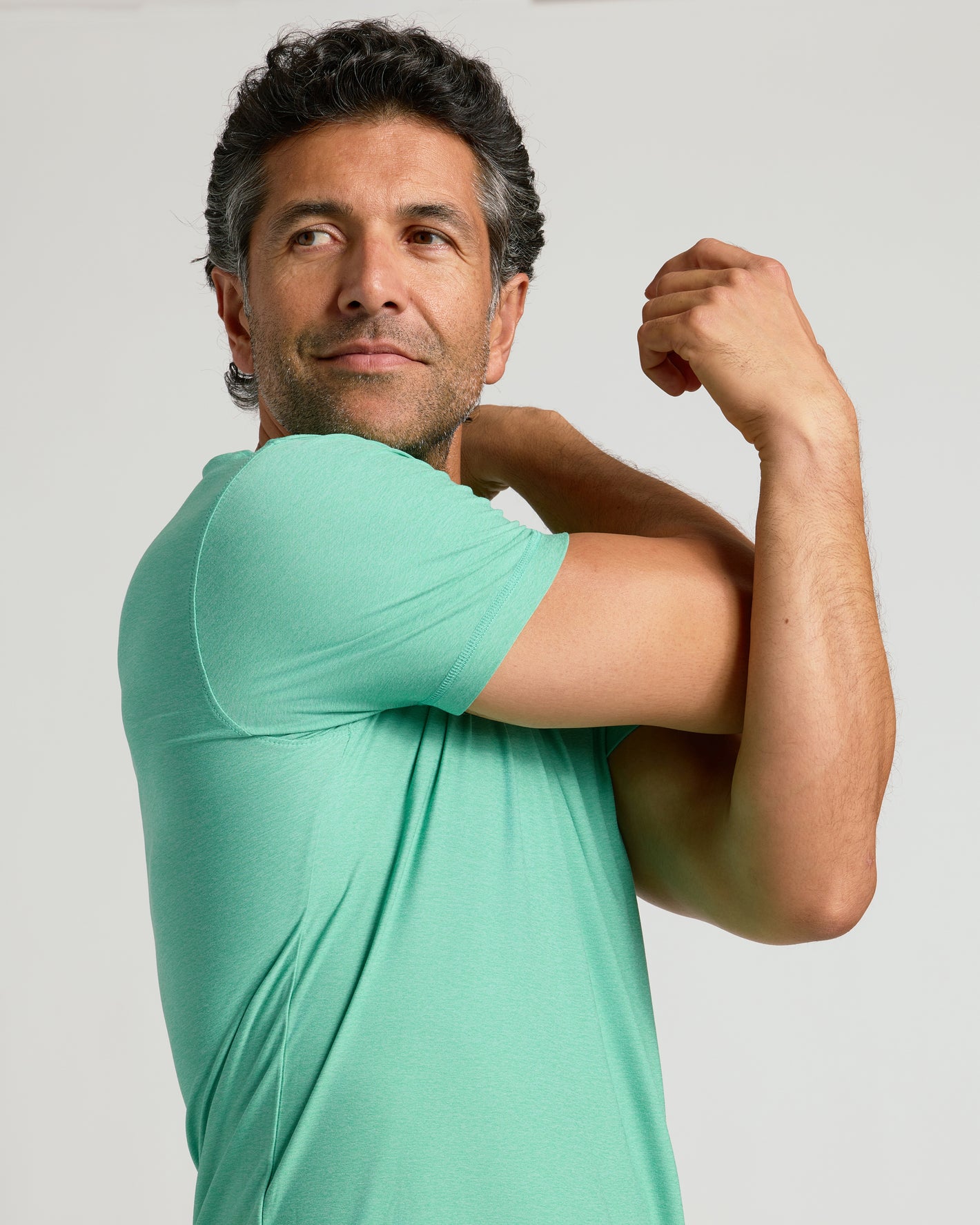 Fern Active Crew Neck Tee on man, stretching shoulder.