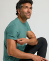 Man wearing Evergreen Active Crew Neck Tee, seated thoughtfully.