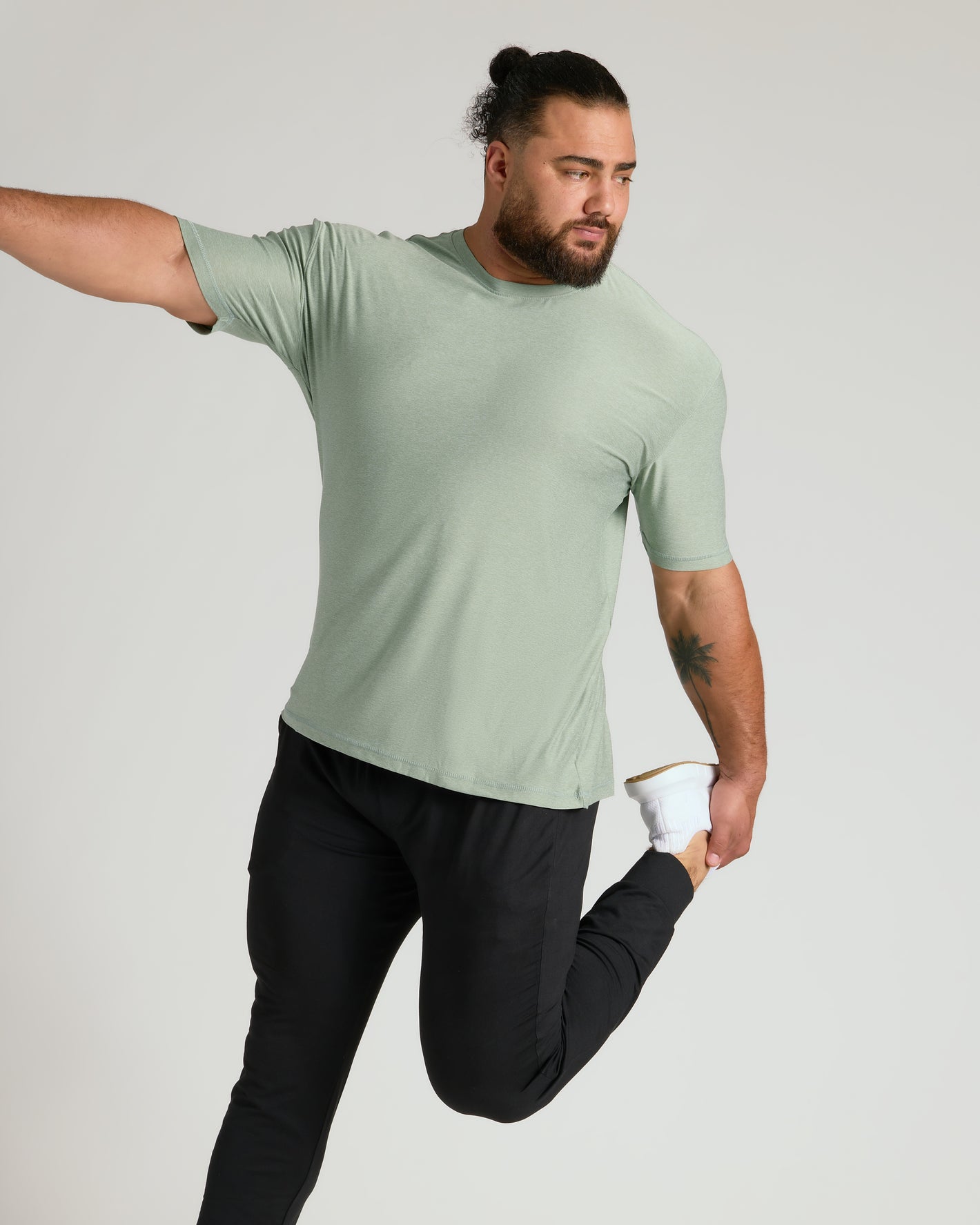 Man stretching in Lichen Active Crew Neck Tee.