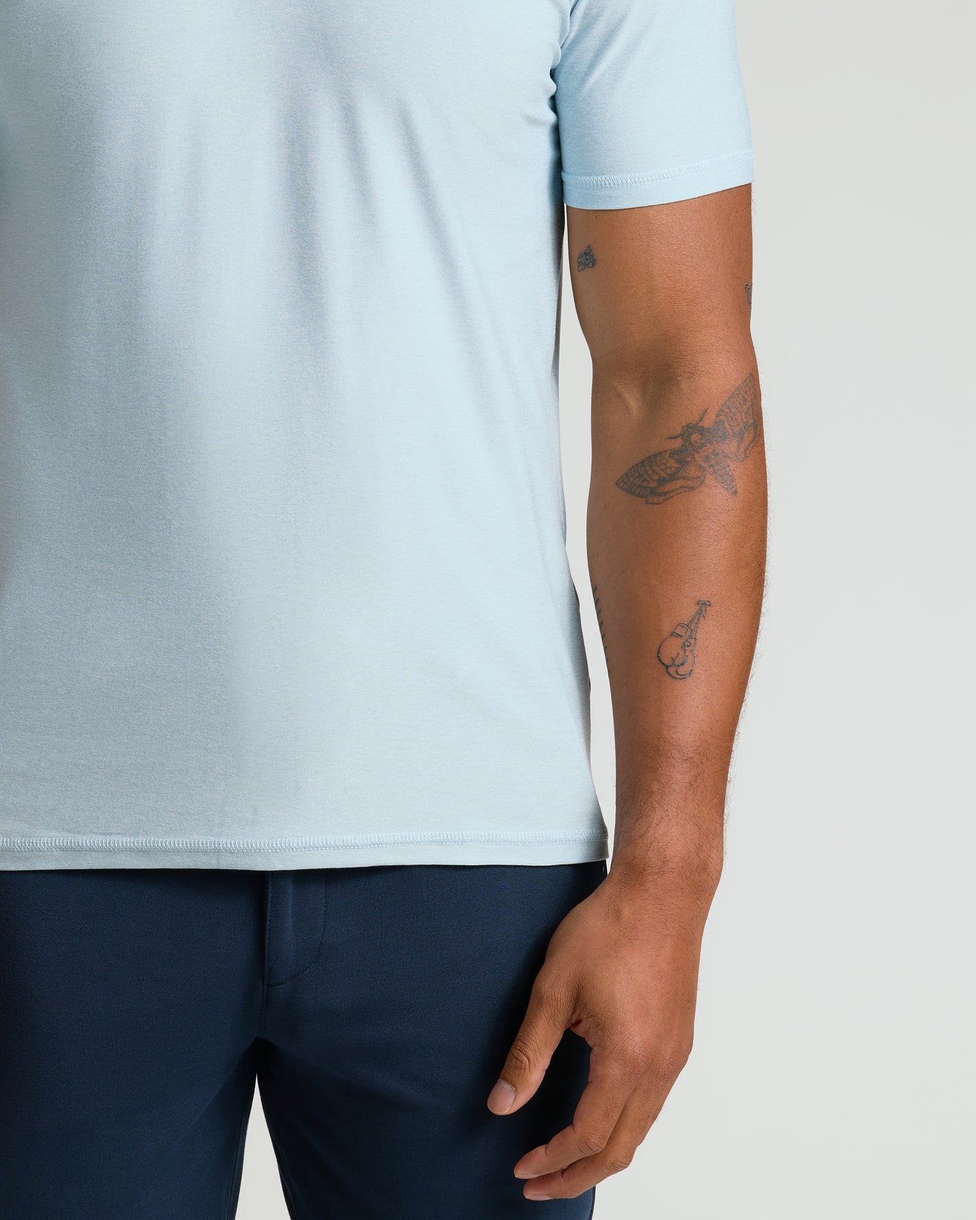 Person wearing Arctic Active Polo 2.0 with visible tattoos and navy trousers.