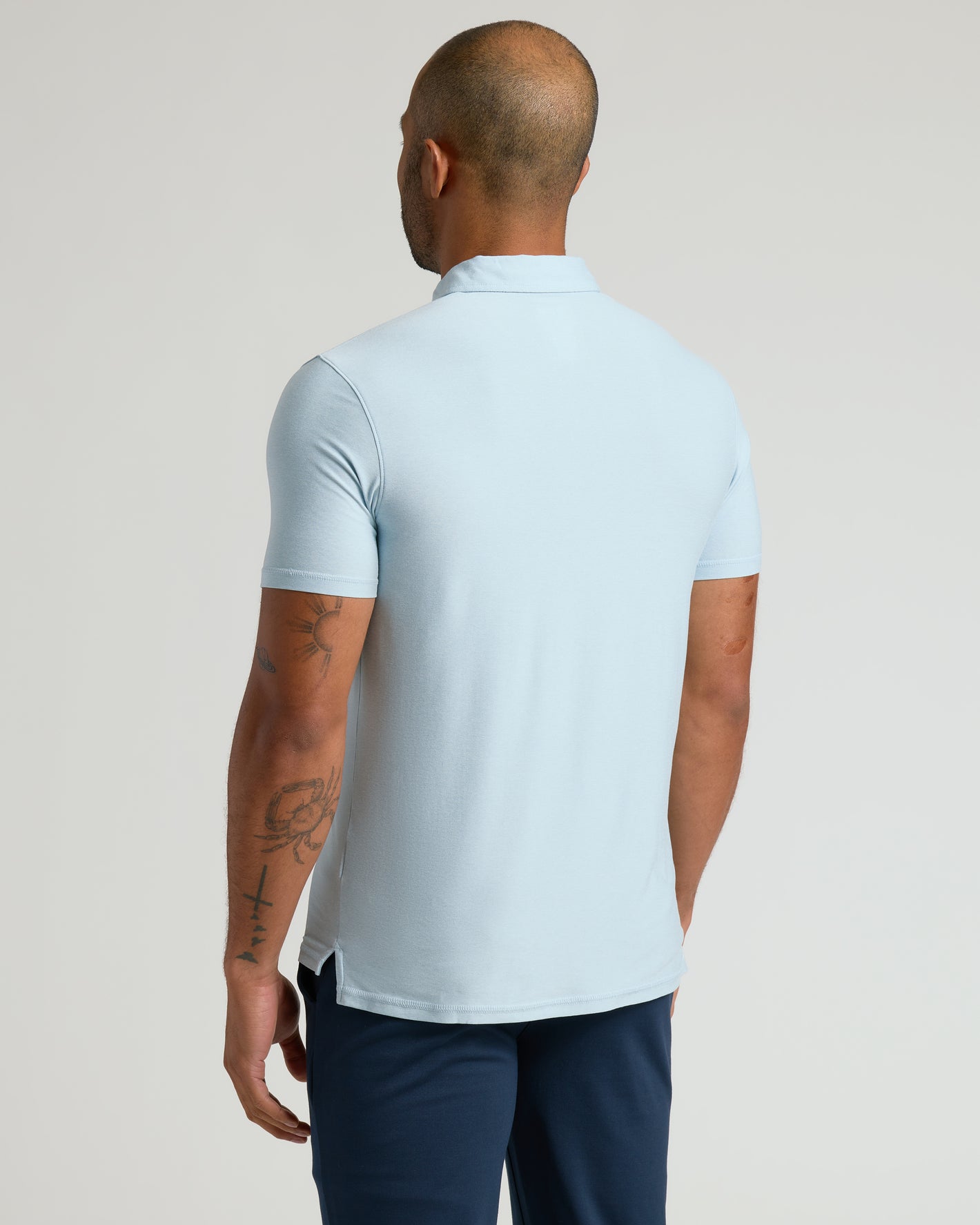 Back view of man in Arctic Active Polo 2.0, showcasing tattoos.