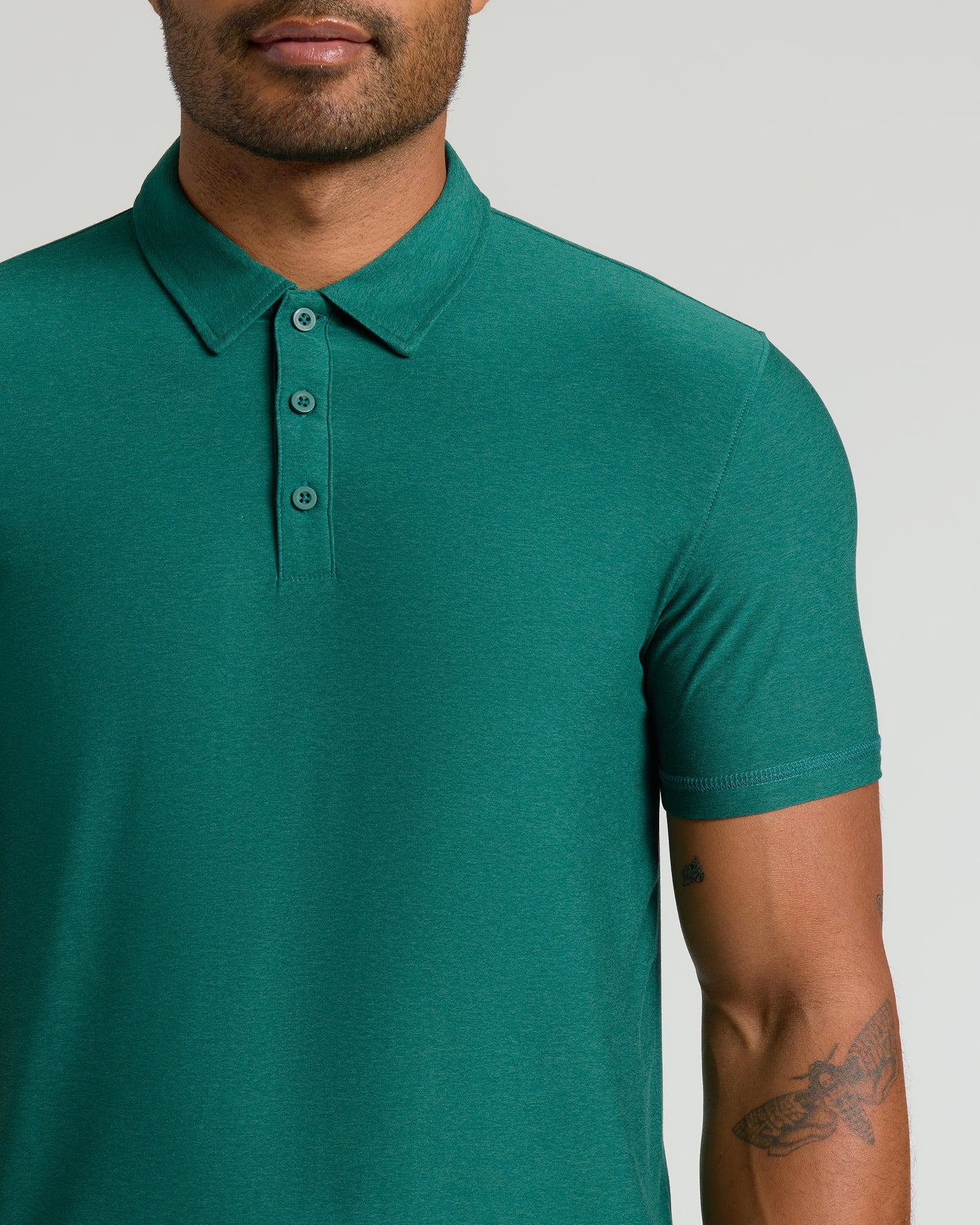 Man wearing Clover Active Polo 2.0, emerald-green, short-sleeve, three-button design.