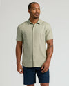 Model in The Staple Short Sleeve Linen Shirt, light sage-green, with navy shorts.