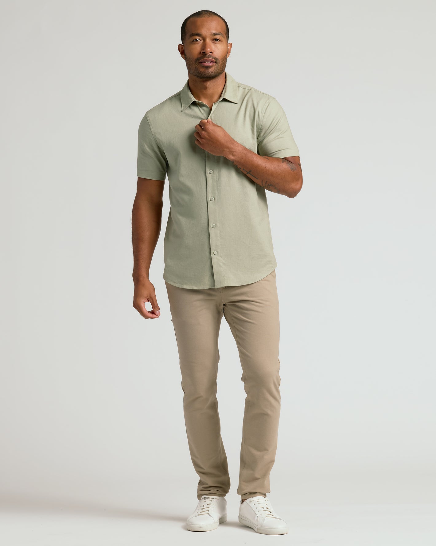 Man wearing Mossy Oak Short Sleeve Linen Shirt, beige chinos, white sneakers.