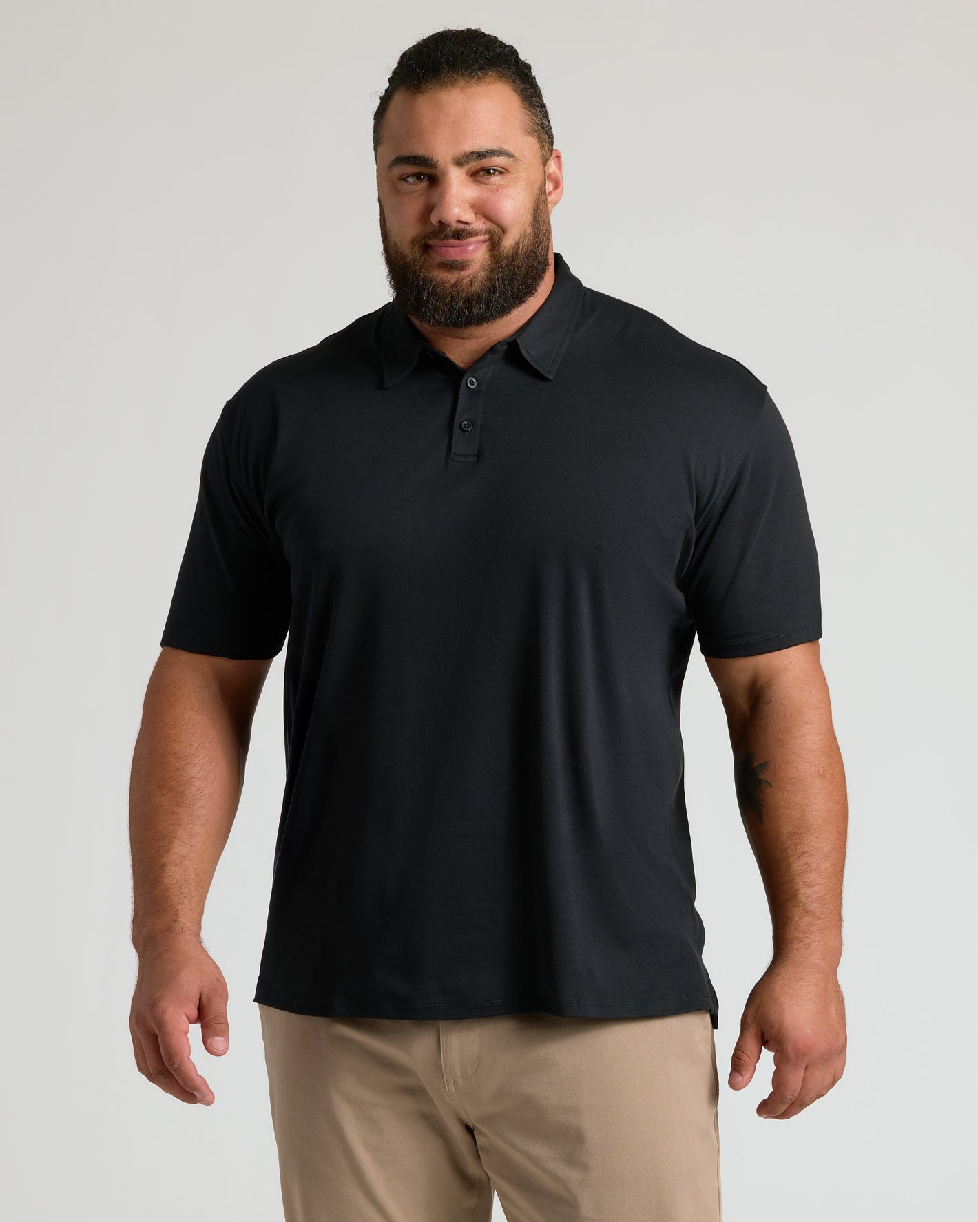 Man models Black Premium Pima Polo 2-Pack with khaki pants.