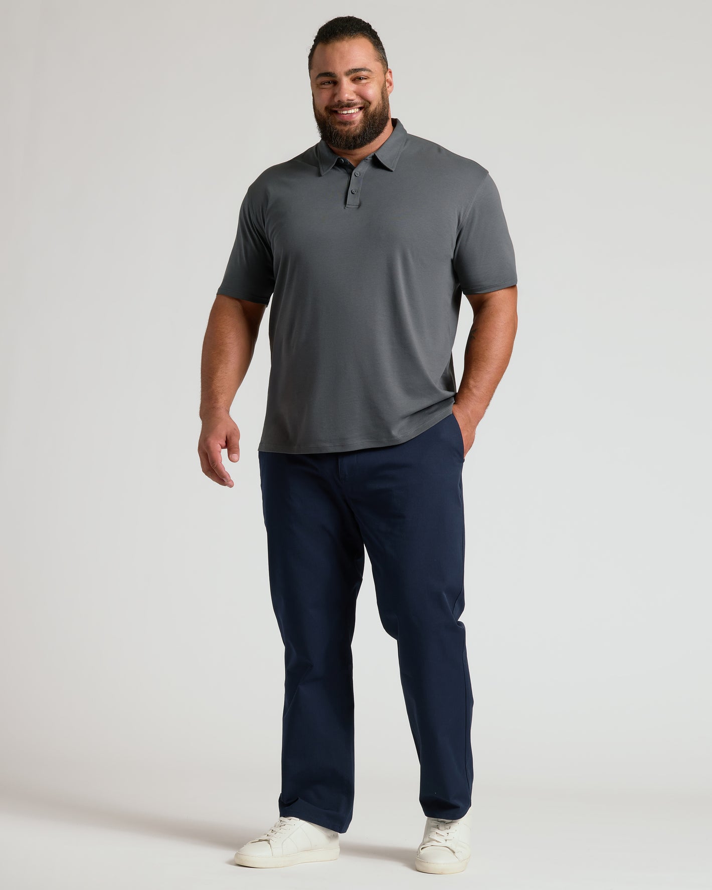 Man wearing Carbon Premium Pima Polo with navy trousers and white sneakers.