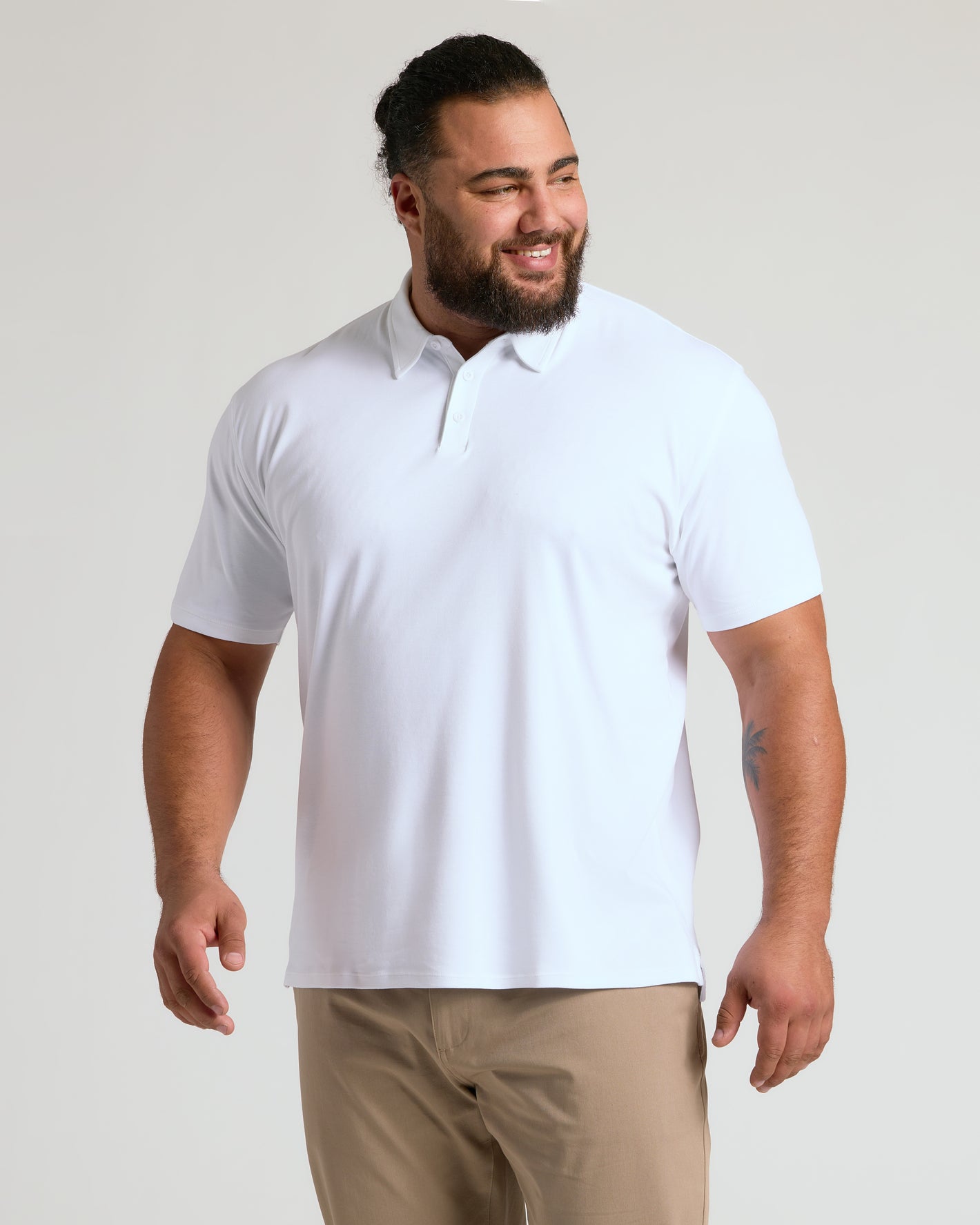 White Premium Pima Polo on smiling man, tailored fit, light background.