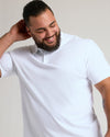 Man in White Premium Pima Polo, relaxed pose, smiling.