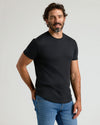 Man wearing Black Premium Pima Crew Curved Hem t-shirt and blue jeans.
