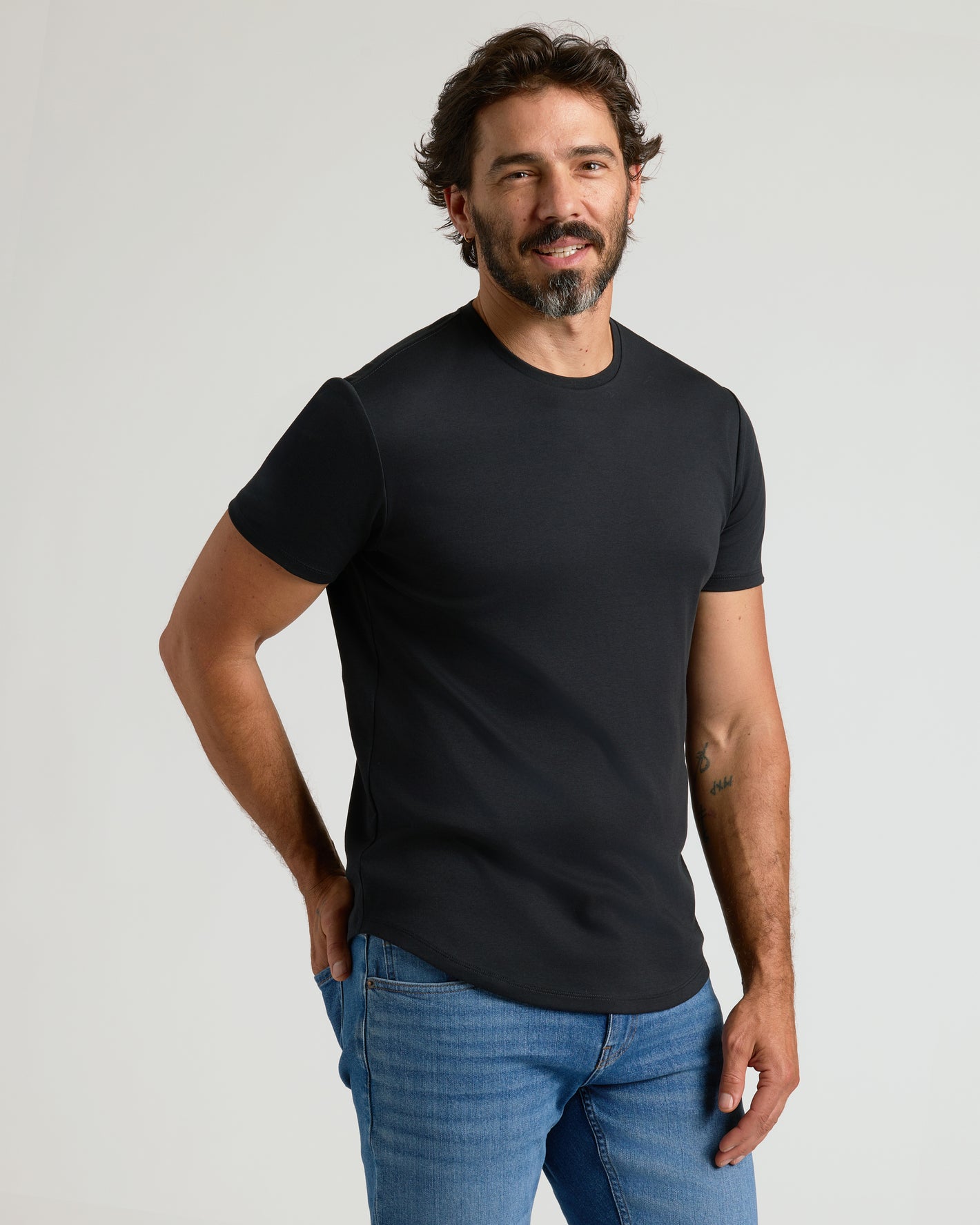 Man wearing Black Premium Pima Crew Curved Hem t-shirt and blue jeans.