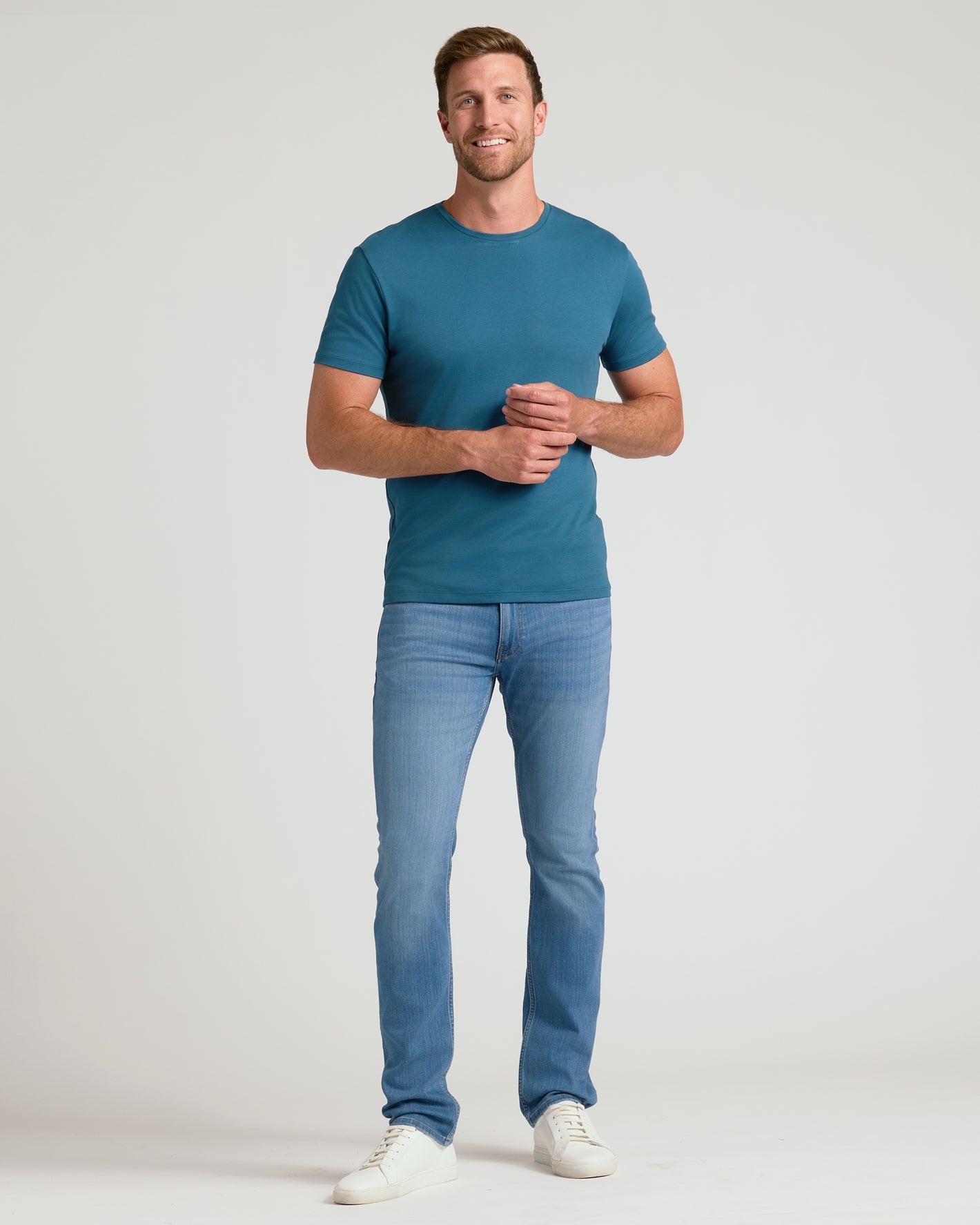 Man wearing Lagoon Premium Pima Crew Neck, slim jeans, white sneakers.