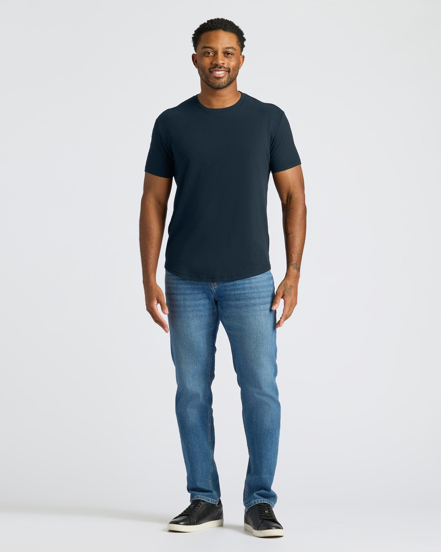 Man wearing a dark blue t-shirt and jeans on a white background