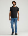 Man wearing a black t-shirt and blue jeans on a white background