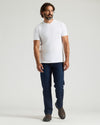 Man wearing a white t-shirt and blue jeans on a light gray background