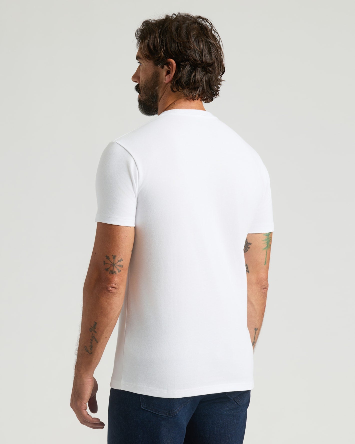 Man wearing a plain white t-shirt on a light gray background