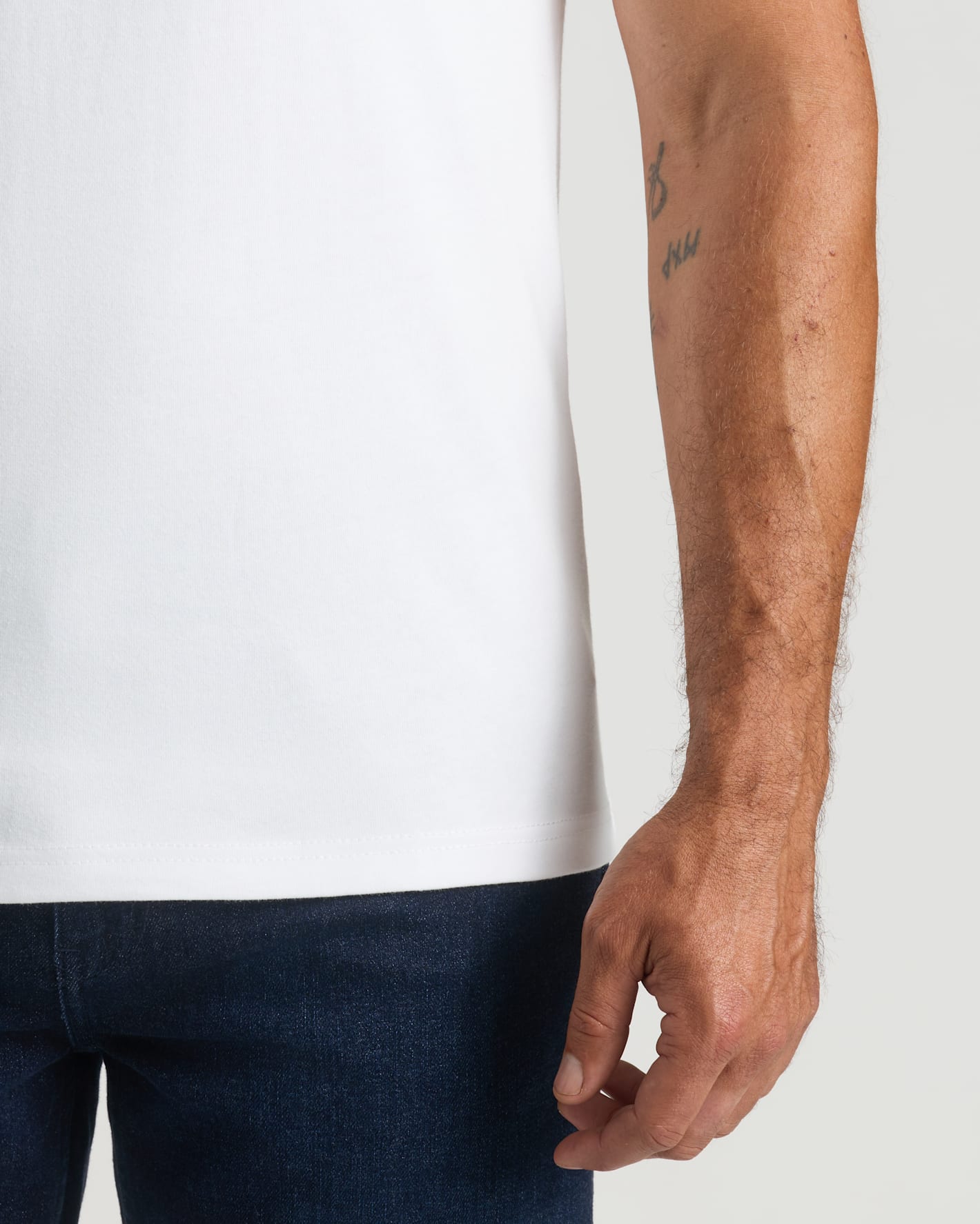 Person wearing a white t-shirt and dark pants with a plain background