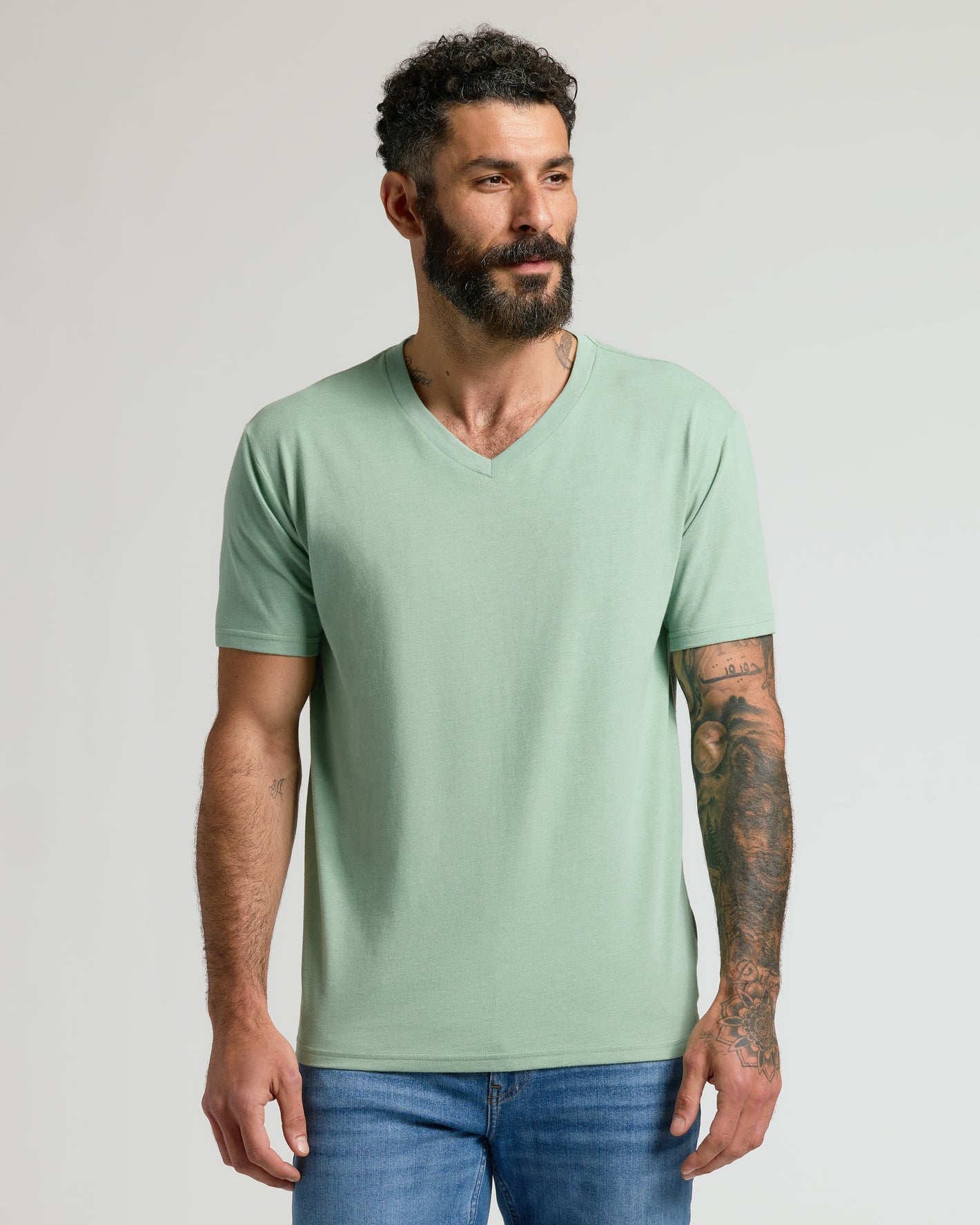 Man in Heather Slate Green Classic V-Neck and medium-wash jeans.